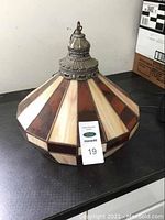 Front side view of stained glass hanging lamp showing amber, cream, and brown glass panels with ornate metal fixture on top and hanging chain.