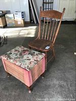Antique spindle back chair and project stool with floral cushion placed on concrete floor.