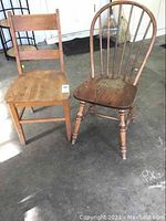Photo of two antique wooden chairs on concrete floor; one with slat back, one with spindle back, showing wear and needing refinishing