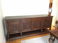 Front view showing full length of carved oak sideboard with four ornate panels and lower shelf