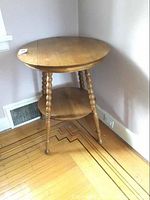 Full view of round wooden side table against wall