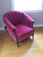 Front and angled view of antique pink velvet upholstered armchair with carved dark wooden legs and frame, showing curved back and rolled arms.