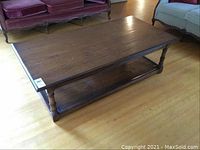 Front angled view of the rectangular solid wood coffee table showing the top surface, turned legs, and lower shelf.