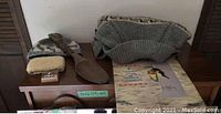 Photo showing wool tuque/hat, sheepskin purse, wooden carved spoon, beaded jewelry, and a Chris Toffersey print on wooden surface.