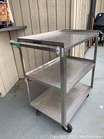 Full view of three-shelf stainless steel cart on casters
