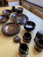 Full view of the entire set showing platter, bowls, plates, cream and sugar containers in brown Basque stoneware