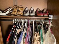 Four pairs of shoes on upper shelf above assorted garments on hangers