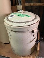 Front and side view of vintage Medalta 8 gallon crock with lid, showing exterior condition, side handle with missing wooden grip.