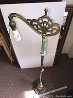 Full view of the antique ornate cast iron floor lamp with visible pull chain and base on carpet.