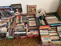 Overview of boxed paperback books with visible titles like 'Star Trek', 'The Da Vinci Code', 'My Brother Lech Walesa', and 'Hot Rods' calendars