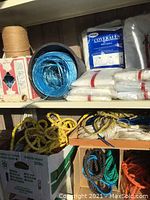 Shelf with coils of rope in multiple colors and sealed packs of disposable coveralls