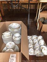 Box with stacks of plates and loose cups on board