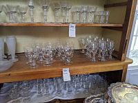 Clear glassware arranged on wooden shelves, showing 15 water goblets and 12 wine glasses.