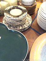 Staked dishes including patterned plates, white bowls, and green platter visible.