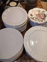 Photo showing stacked plates in three groups: plain white, white with textured edge, and scalloped floral