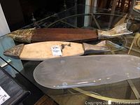 Three fish-shaped platters arranged on a glass table demonstrating their size and material differences.