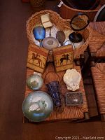 Full view of vanity items spread on wooden chair, including carved wooden bookends with horses, ceramic dishes, blue glass vase with metal chain, white ceramic heart basket, hand mirrors and trinket box.