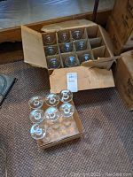 Photo showing two open cardboard boxes filled with wine glasses. One box has stemmed glasses.