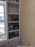 Shelf displaying multiple tins of varying shapes and decorative designs, including round, oval, and rectangular tins with portraits and floral imagery.