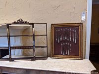 Overall view showing metal curio shelf on left and framed flatware sampler on right
