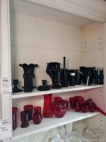 Shelf with various black glass items including vases, an ice bucket, salt and pepper shakers, and candle holders.