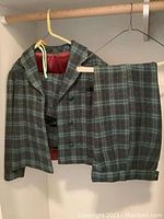 Plaid pants and matching jacket hanging on hangers showing the pattern and fabric quality.