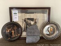 Group photo showing the framed papyrus, two decorative plates, and stone artifact replica arranged on a flat surface.