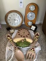 Group photo showing the ceramic mushroom clock, matching salad spoons, round wall clock, wooden clock with hygrometer and thermometer, and two vintage alarm clocks, one black with cracked glass, one beige with broken case.