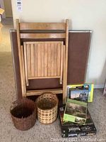 Photo of wooden folding chair leaning against folding card table with three baskets and three puzzles arranged in front.