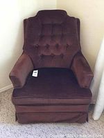 Front view of brown upholstered swivel tilter chair showing tufted backrest and cushioned seat.
