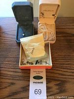 Three open jewelry boxes showing an opal pendant necklace, a pearl necklace with detachable clasp, and assortment of loose pearls in a box labeled Peoples and Azoles.