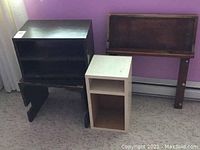 Three items together - a brown half easel, white storage cabinet, and dark wood shelf against wall