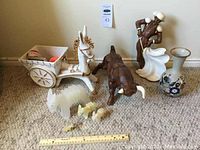 Wide shot showing all items: ox cart, bull, animal figure set, person figurine and vase