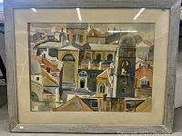 Front view of framed watercolor painting showing detailed cityscape with geometric rooftops and buildings.