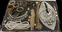 Top view showing full jewelry lot with pearl necklaces, different bracelets, rings and metallic mesh necklace.