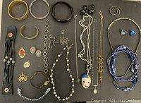 Full assembly of jewelry lot on black surface showing various bracelets, necklaces, earrings, pendants, and a headband.