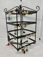 Photo showing front and side view of black metal rotating earring display loaded with assorted pairs of earrings in various colors and styles