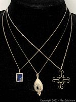 Three sterling silver pendant necklaces displayed on black velvet background, showing length and arrangement of pendants and chains.