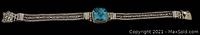 Full length view of the Sarda sterling silver bracelet showing the blue-green stone center and Byzantine chain.