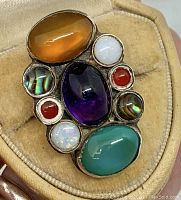 Front view of the multi-stone ring showing the variety of stones set in silver, including opals, carnelian, mother of pearl, amethyst, green chalcedony and two unidentified stones.