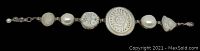 Full length top view of the bracelet against a dark background, showing the sequence of carved mother of pearl and faux pearl links with toggle clasp.