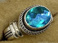 Close-up of oval faceted blue/green stone set in twisted rope bezel
