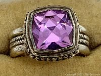 Close-up photo of ring face showing large square-cut pink faceted stone set in a raised bezel with beaded detailing.