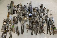 Full lot of assorted silver plate flatware and serving pieces spread out on a surface showing variety and condition.