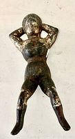 Top view photo showing the full body of the cast iron female figure boot jack with arms behind head and legs spread, illustrating surface wear and patina.