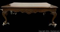 Side view of coffee table showing claw feet on casters and carved apron detail