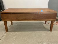 Full front view of the cherry coffee table showing the drop leaf unfolded and the table's rectangular shape and tapered legs.