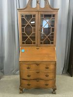 Full front view of the one-piece wooden secretary with china cabinet, showing glass doors and drawers below.