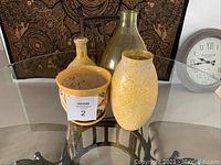 Photo showing front angle view of four vases and a centerpiece pot on glass table.