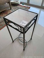 Front view of metal and glass tall stand showing design details and glass top.